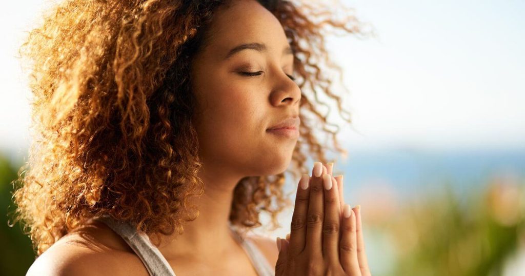 Woman practicing mindfulness with hands clasped in prayer pose, symbolizing inner strength, emotional balance, and self-discovery during Dry January.