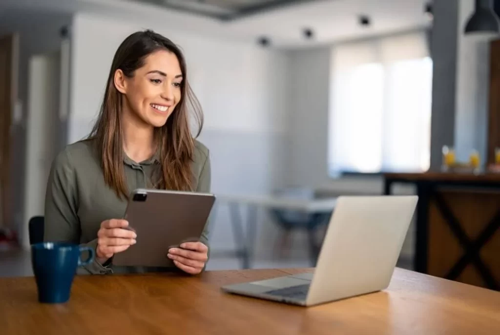 a woman in a green shirt sitting in front of a computer with a cup of coffee or tea coaching the self-made u community
