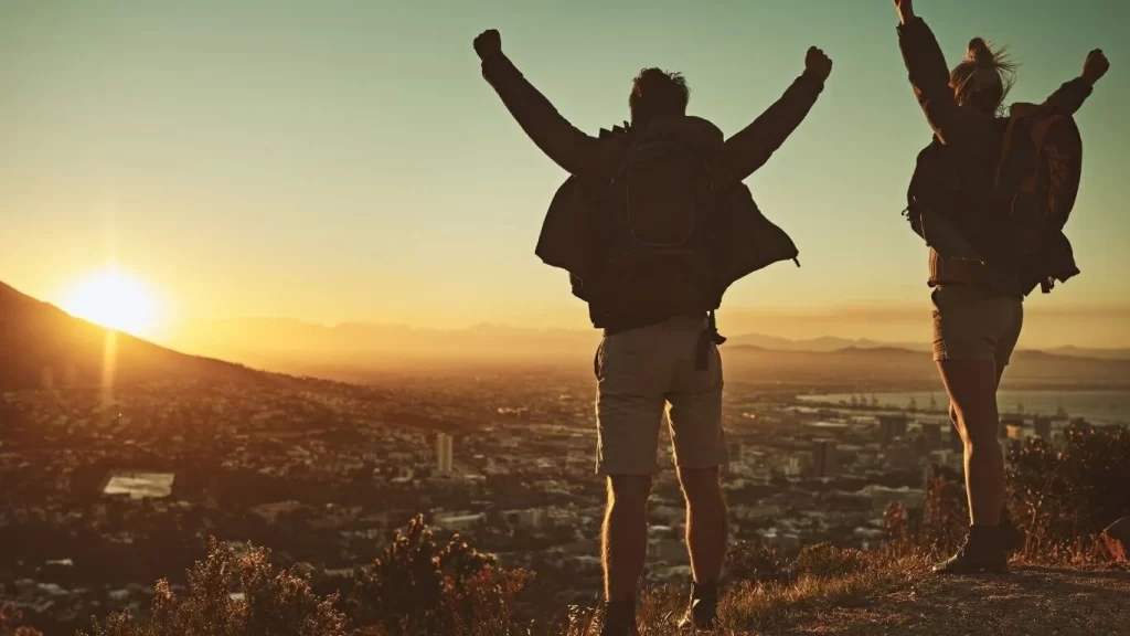 A couple on a hill celebrating at sunset